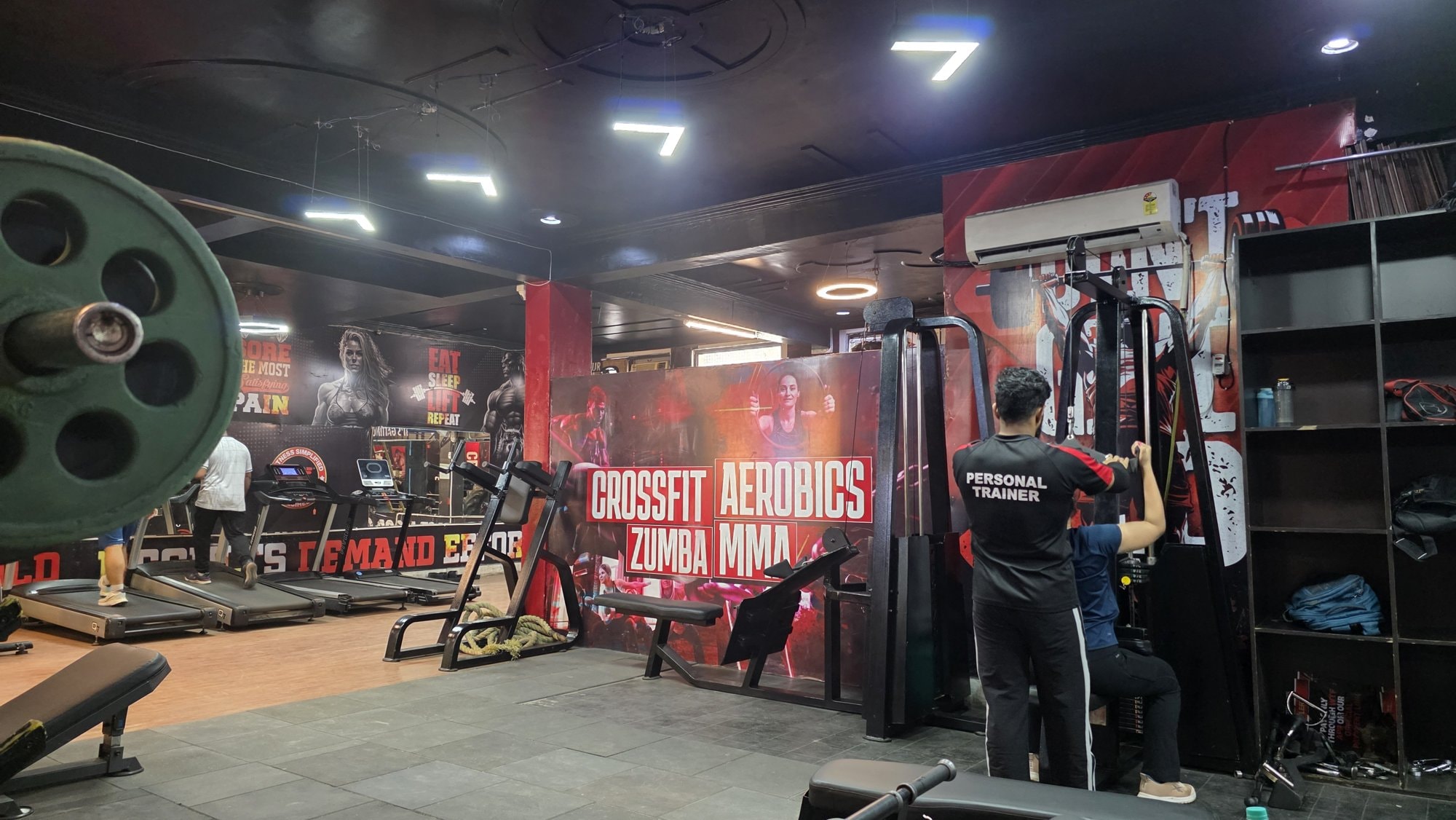 A trainer guiding a member on a cable machine at a WTF gym