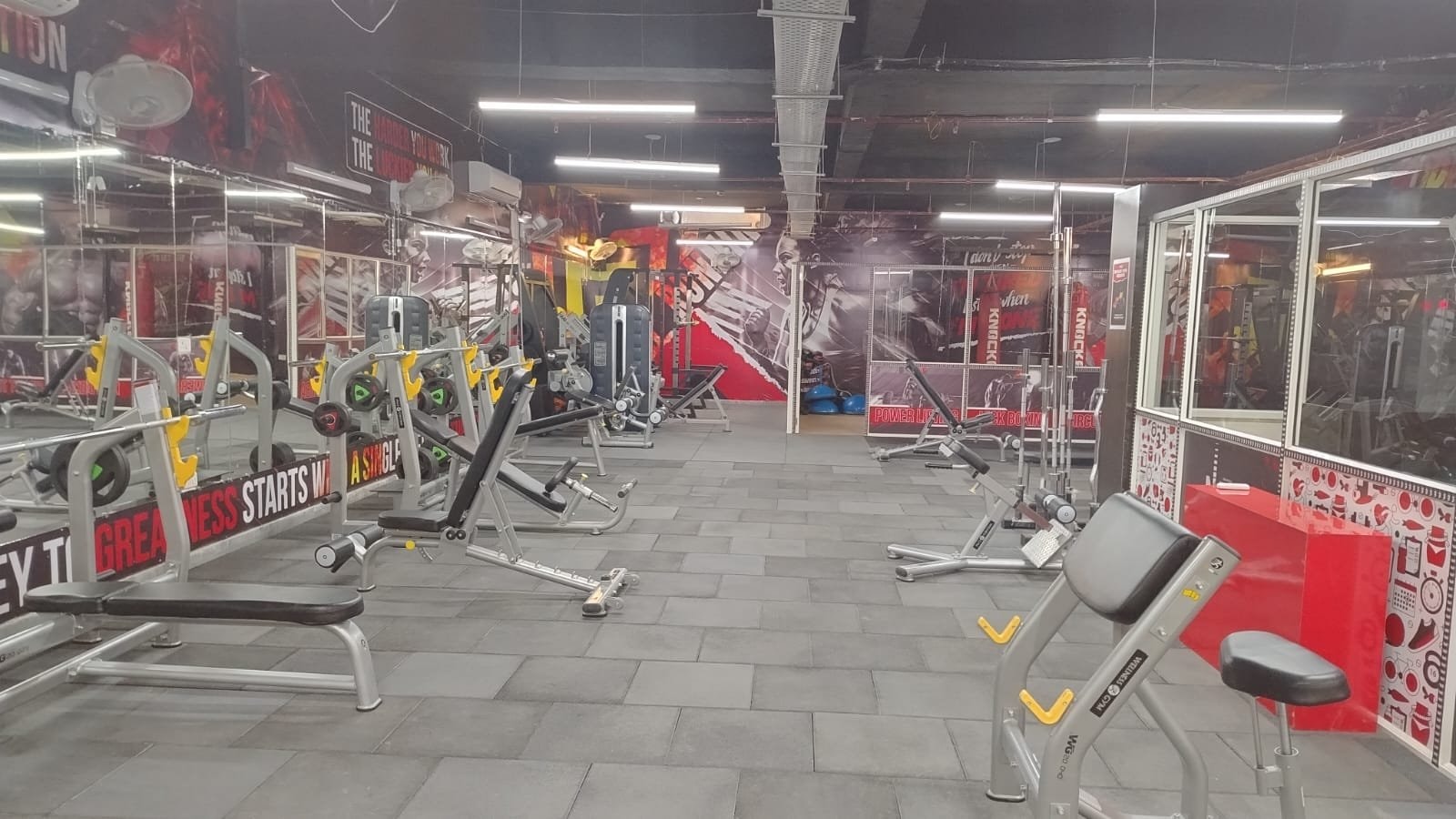 A preacher curl bench in front of the strength floor of a WTF gym